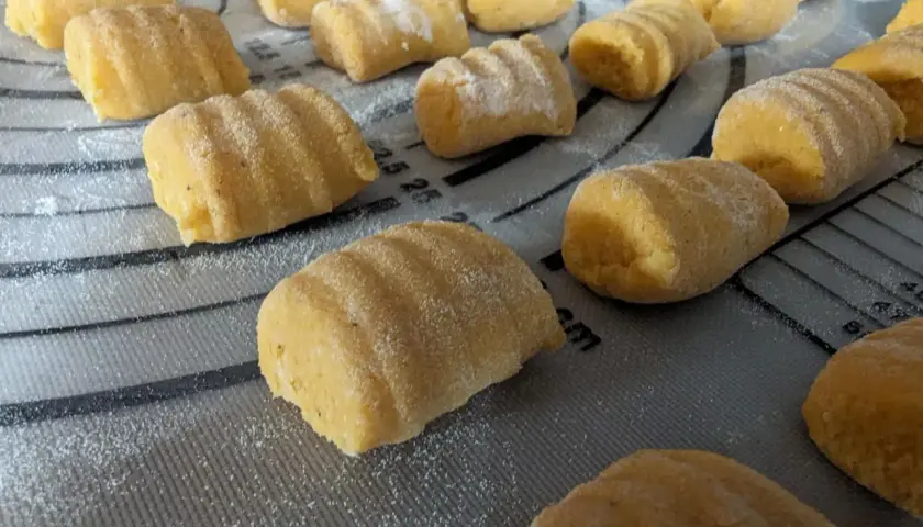 Gnocchi de patate douce faits maison, prêts à être cuits, saupoudrés de farine sur une planche.