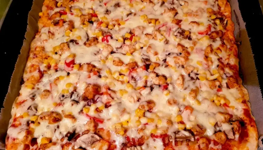 Prostokątna pizza z kurczakiem, kukurydzą, papryką i serem.
