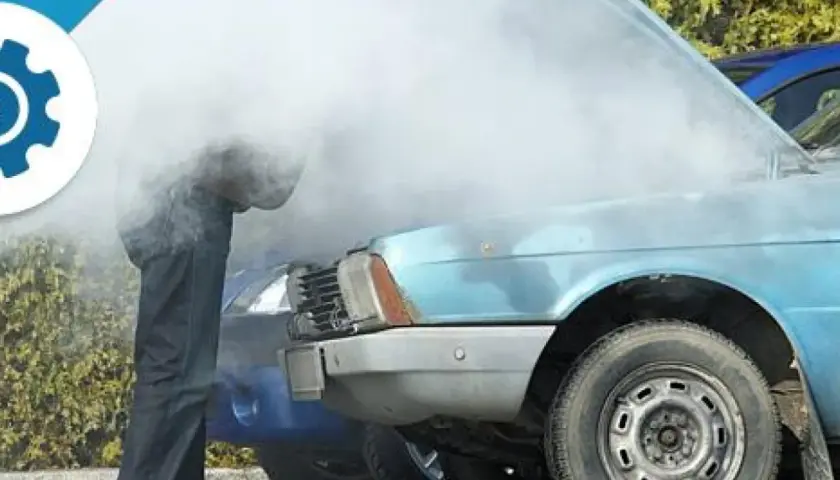 Uomo guarda motore fumante di un'auto blu, probabile perdita liquido refrigerante.