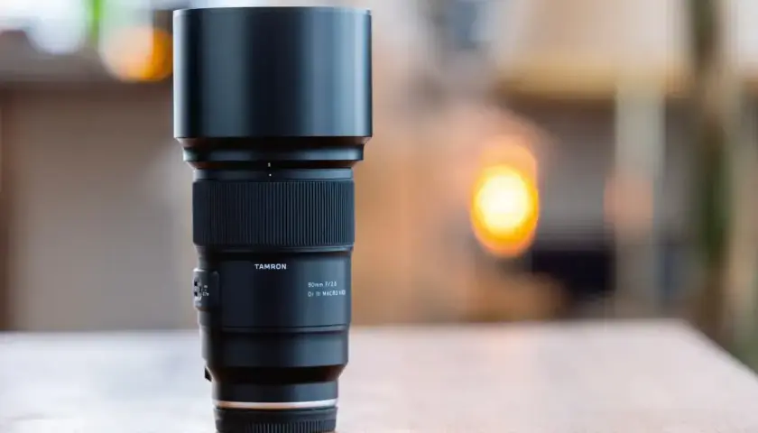 Obiektyw Tamron 90mm f/2.8 Di III MACRO VLD, idealny do fotografii w **trybie makro**, z charakterystycznym pierścieniem ostrości i osłoną przeciwsłoneczną.