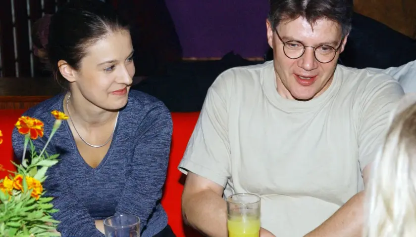 Mirosław Konarowski w prywatnym życiu, uśmiechnięty, siedzi przy stole z kobietą.