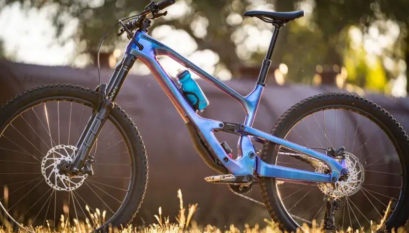 A stunning 2018 Cannondale Jekyll mountain bike with a iridescent blue frame, parked in golden hour light.