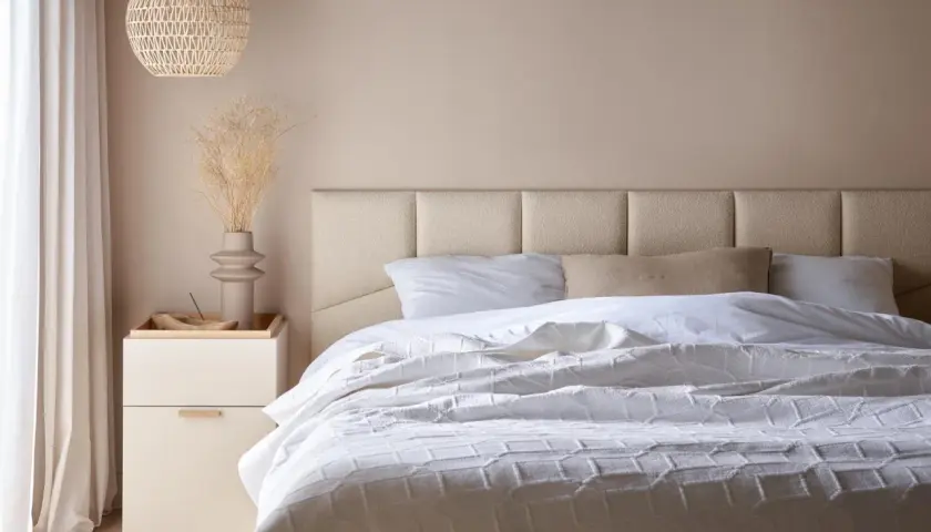 Miękkie, tapicerowane panele tworzą elegancki **pomysł na zagłówek do łóżka**. Jasna kolorystyka i minimalistyczny design.
