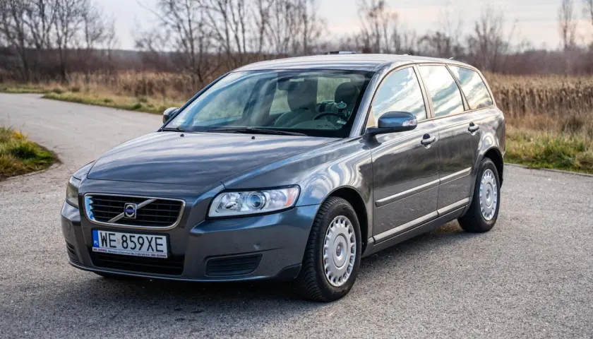 Szary Volvo V50 2.0D na drodze, otoczony jesienną przyrodą.