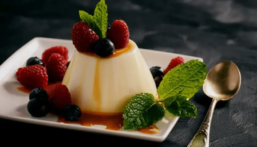 Panna cotta z malinami i borówkami, polana syropem. Idealny deser, gdy szukasz prostego panna cotta przepis.