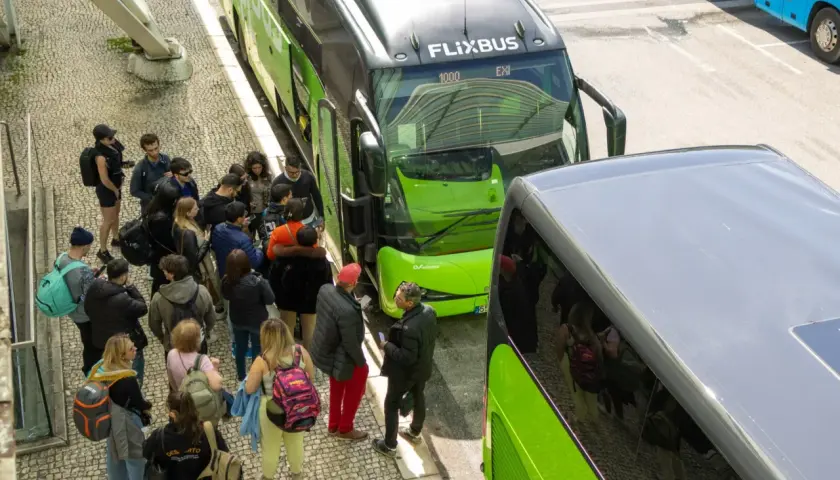 Grupa ludzi czeka na zielonego Flixbusa, szukając okazji na podróż.