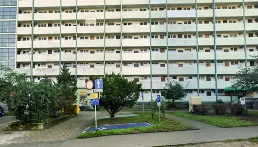 Wyznaczono miejsce dla niepełnosprawnych bez koperty, obok zieleni i bloków mieszkalnych.