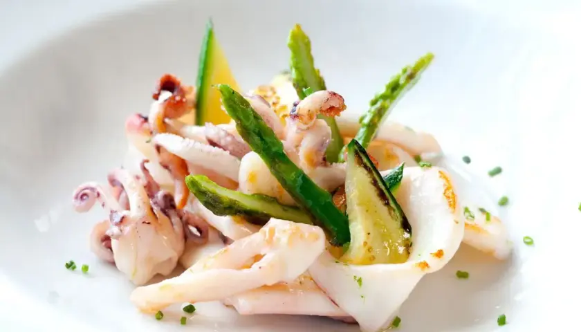 Deliziosa insalata di seppie gourmet con asparagi croccanti e zucchine grigliate, guarnita con erba cipollina.
