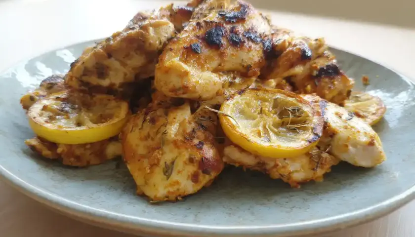 En tallrik med saftig, ugnsbakad marinerad kyckling med citronskivor.