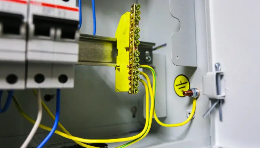 Instalacja elektryczna z wyłącznikami i listwą zaciskową. Pokazuje, jak zrobić uziemienie szpilkowe, łącząc przewody z listwą i obudową.