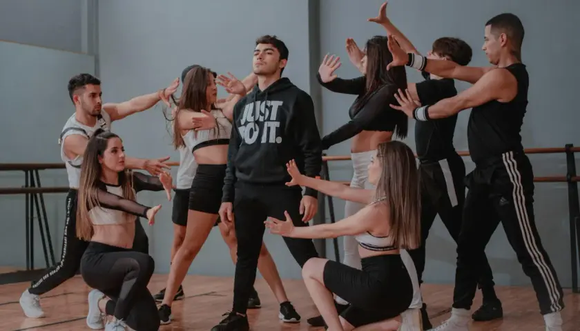 Un gruppo di giovani ballerini in abiti sportivi esegue una coreografia di danza pop in uno studio.