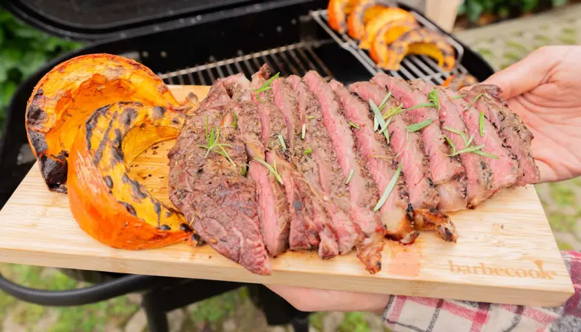 Un steak grillé et des quartiers de potimarron barbecue, servis sur une planche en bois.