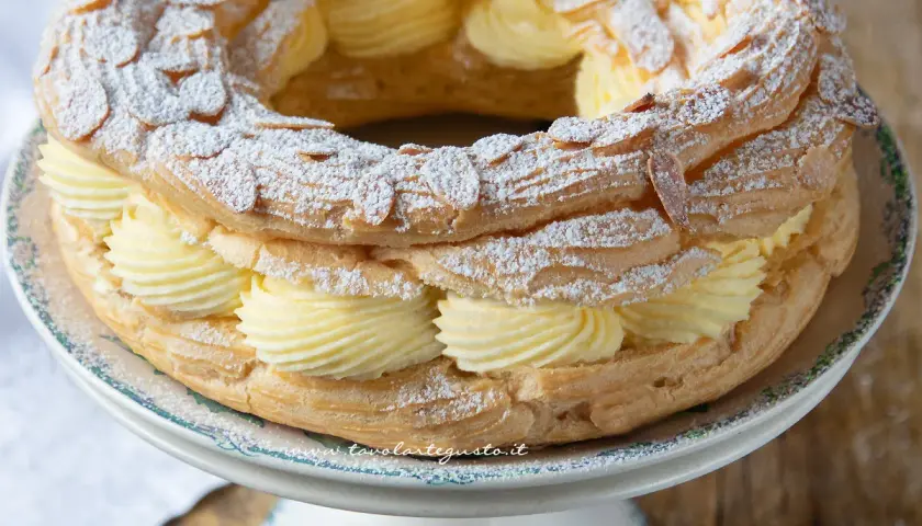 Un delizioso Paris Brest, un anello di pasta choux ripieno di crema pasticcera e guarnito con mandorle e zucchero a velo.