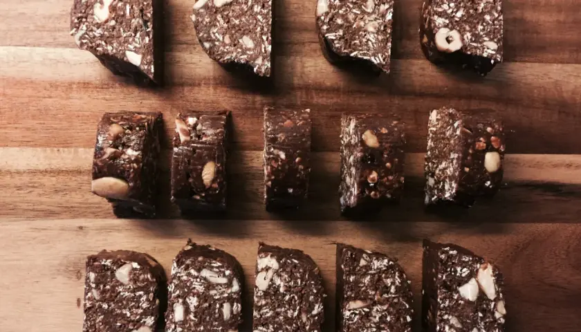 Chokladiga egna bars med nötter och kokos, upplagda på en träskärbräda.