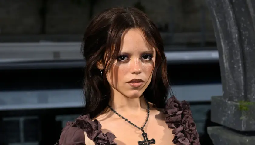 Jenna Ortega, znana z roli Wednesday, ma 160 cm wzrostu. Na zdjęciu ma ciemne włosy i krzyż na szyi.