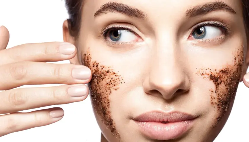 Une femme applique un gommage visage à base de grains de café. Elle montre comment faire un gommage visage pour une peau douce.