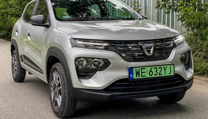 Srebrna Dacia Spring z zieloną tablicą rejestracyjną. Ten elektryczny samochód oferuje dobry zasięg na jednym ładowaniu.
