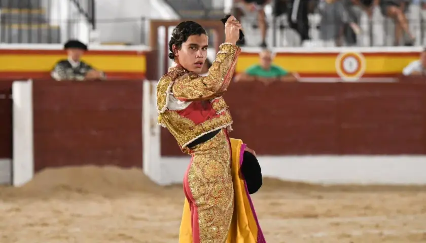 Joao Ferreira, banderillero, con traje de luces dorado y rojo, sostiene un capote en la plaza de toros.