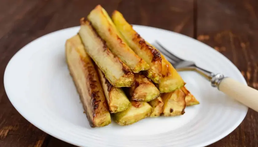 Zucchine in carpione dorate e succulente, impilate su un piatto bianco, pronte per essere gustate.