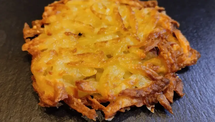 Un croccante rosti di patate dorato, preparato con patate grattugiate e cotto fino a ottenere una deliziosa crosticina.