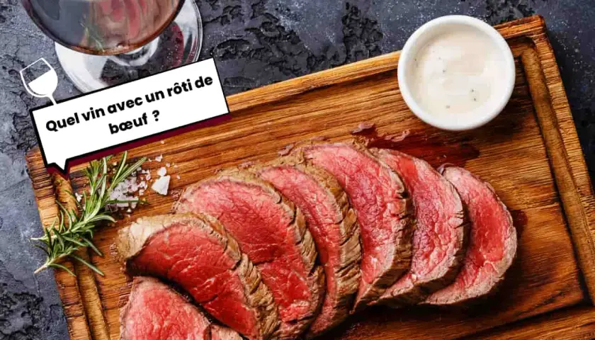 Un verre de vin rouge accompagne un rôti de bœuf tranché, prêt à être dégusté. Une question se pose : quel vin choisir pour ce plat savoureux ?