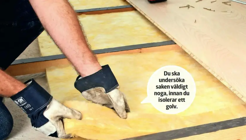 Händer med handskar lägger isolering med papp på ena sidan i ett golvbjälklag. Verktyg och golvbrädor ligger redo.