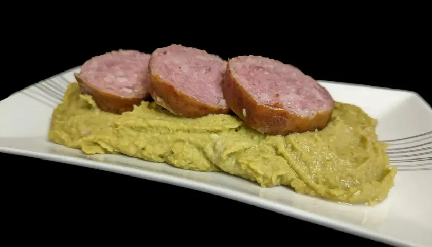 Trois tranches de saucisse sur une purée de pois cassés, un plat réconfortant.