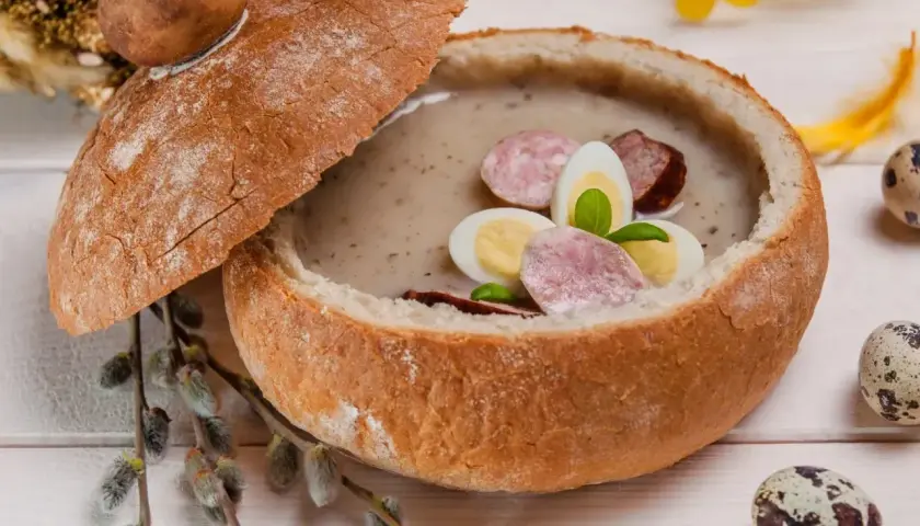 Zupa biały barszcz w chlebie, ozdobiona jajkiem i kiełbasą. Idealna, gdy zastanawiasz się, jak odkwasić zupę.