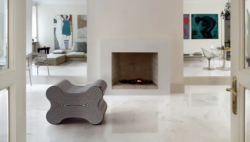 Pavimento rettificato: pro e contro. Un salotto moderno con camino, opere d'arte e un particolare divano a forma di osso.