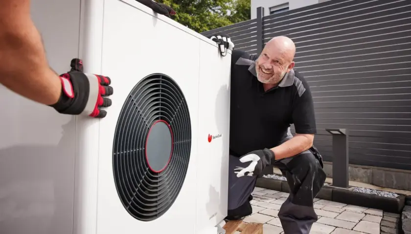 Un technicien souriant aide à installer une pompe à chaleur air air, un système efficace pour le confort de votre maison.