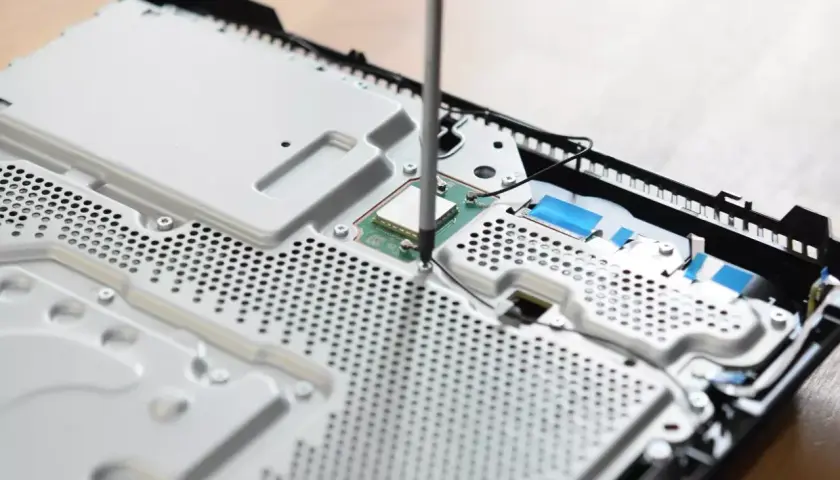 Uczeń technikum podczas praktyk zawodowych skręca konsolę.