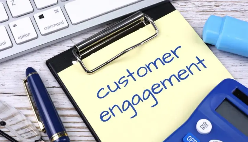 Notatka z napisem "customer engagement" obok klawiatury, długopisu i kalkulatora.