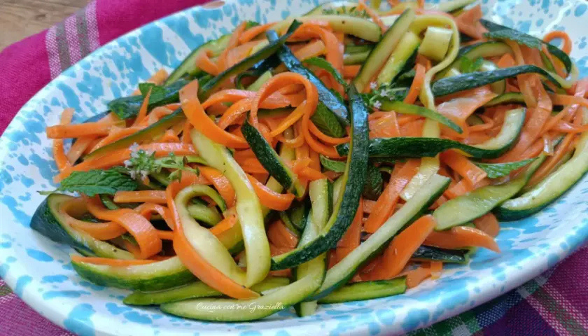 Deliziosa insalata di zucchine e carote a julienne, guarnita con menta fresca. Un piatto leggero e colorato.