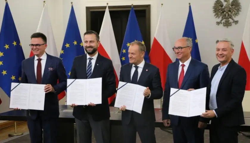 Pięciu mężczyzn w garniturach trzyma dokumenty. To tekst umowy koalicyjnej, symbol porozumienia.