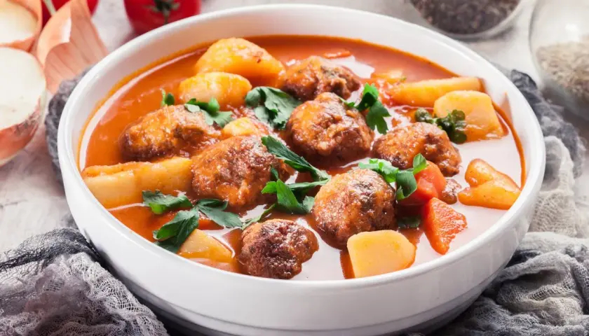 Zupa klopsowa babci: aromatyczne klopsiki w pomidorowym sosie z ziemniakami i natką pietruszki.
