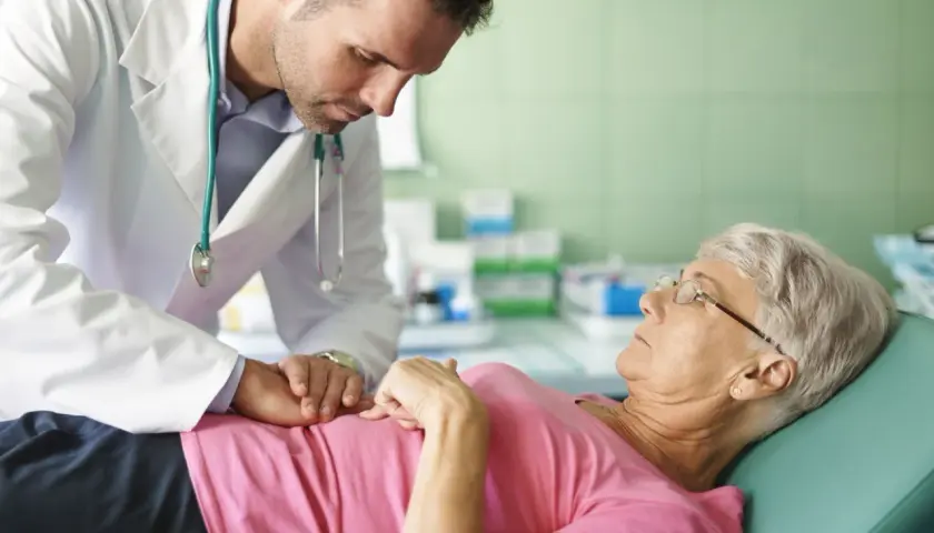 Lekarz bada pacjentkę, która skarży się na przelewanie w brzuchu. Delikatnie dotyka jej brzucha, próbując zdiagnozować przyczynę dolegliwości.