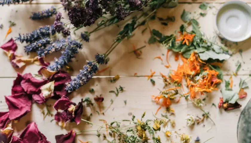 Comment faire sécher des fleurs avec de la laque : roses, lavande, et fleurs oranges séchées sur fond de bois.