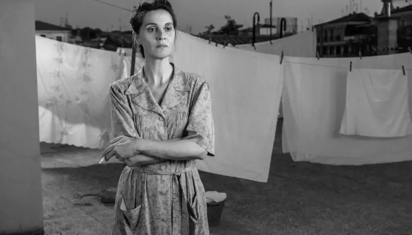 Una donna con un vestito a fiori fuma sul tetto, con panni stesi sullo sfondo. Le recensioni di "C'è ancora domani" lodano la sua interpretazione.