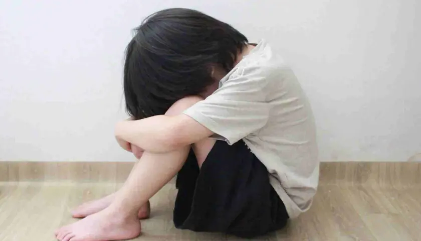 Bambino rannicchiato, un'immagine che evoca la necessità di capire come aiutare un figlio depresso.