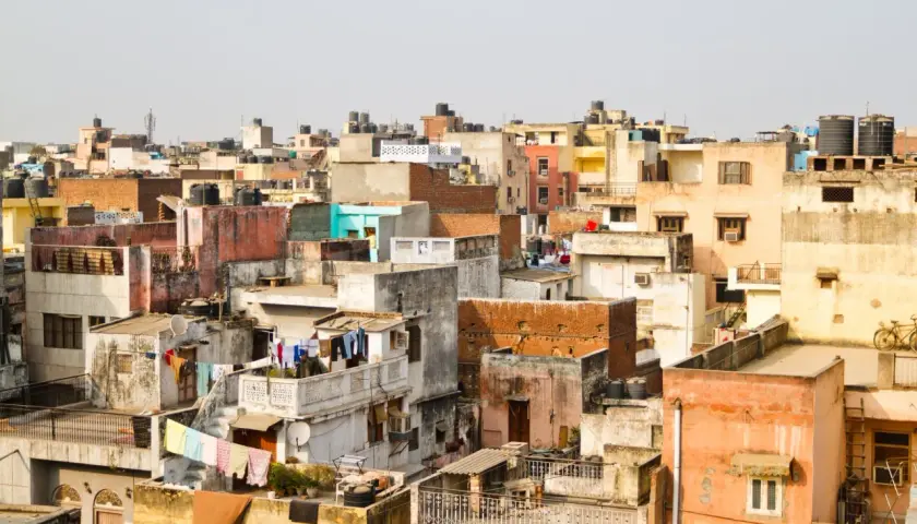 Gęsto zabudowane dachy w New Delhi, świadczące o dużej **new delhi ludność**. Widać pranie rozwieszone do suszenia i zbiorniki na wodę.