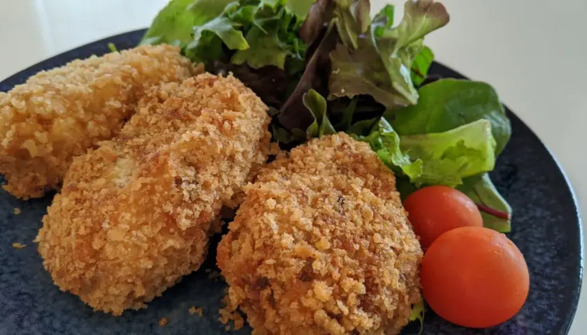 Golden potato croquettes served with fresh salad and cherry tomatoes.