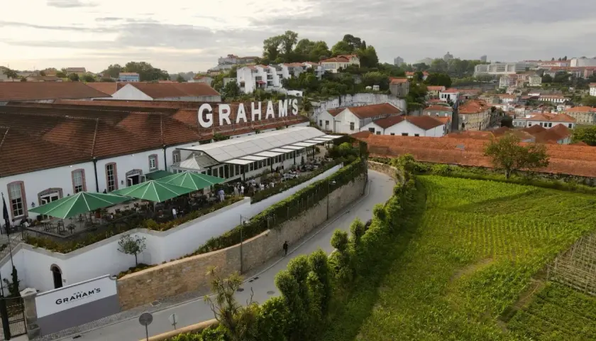 Le vignoble Porto District, avec le nom "GRAHAM'S" en lettres blanches sur le toit, offre une vue sur des bâtiments traditionnels et des champs verdoyants.