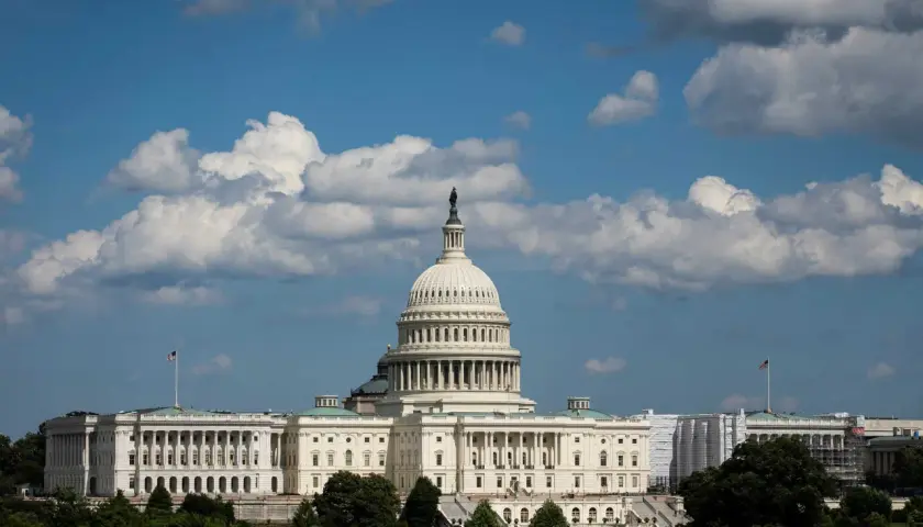 The U.S. Capitol building under a cloudy sky. Members of Congress work within these walls, but do members of Congress have security clearances?
