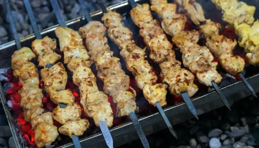 Kebab z mięsa mielonego na patyczkach grilluje się nad żarem. Mięso jest soczyste i apetyczne.