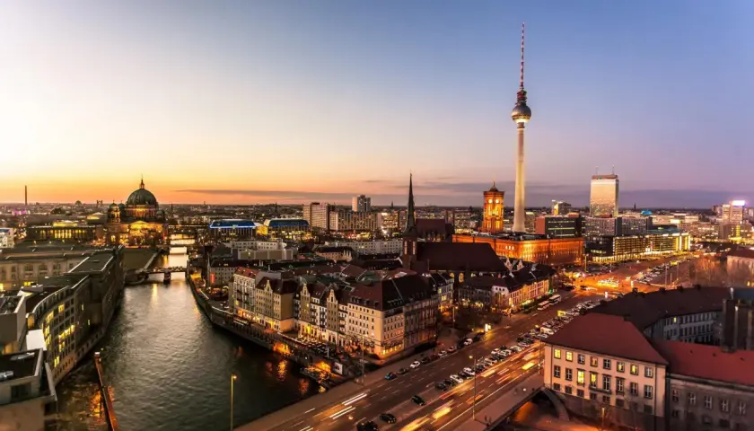 Berlin vid solnedgången. En bro leder över floden, med bilar som susar förbi. En fantastisk utsikt över Tyskland, som kan vara en del av en resa från Danmark.