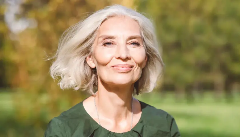 Mujer sonriente con cabello rubio platino, ideal para matizar canas. Su piel irradia luz natural.