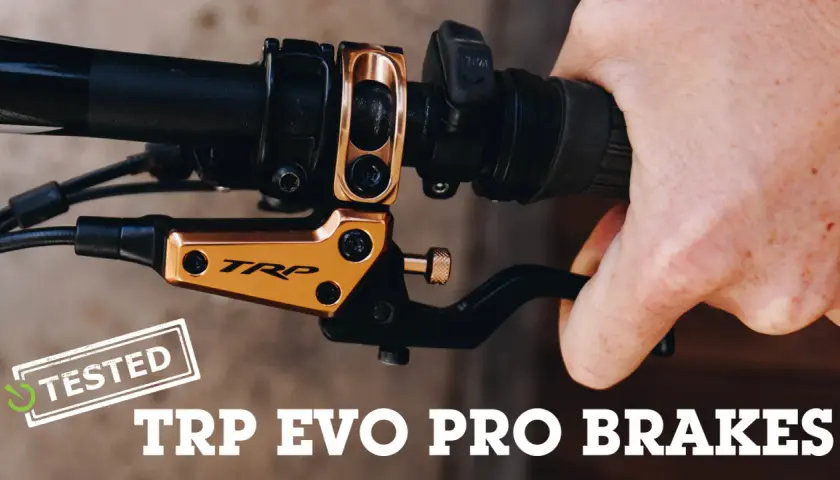 A hand squeezes a black brake lever on a bicycle handlebar. The gold TRP EVO PRO BRAKES are featured in this review.