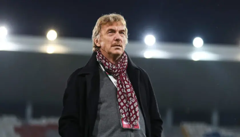Zbigniew Boniek w płaszczu i szaliku na tle stadionu.