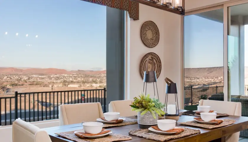 A rustic wooden dining table set for a meal, with a stunning view of a desert landscape. This image inspires how to choose a dining room table for a scenic setting.