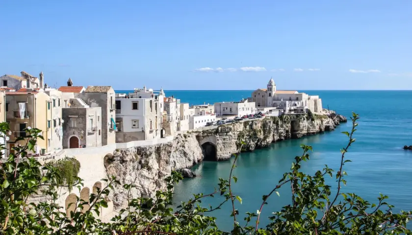 A picturesque coastal town in southern Italy, perfect for a southern Italy itinerary. White buildings cling to cliffs overlooking the turquoise sea.